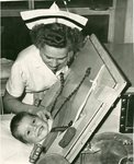 Nurse Assisting Child in Iron Lung
