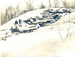 Men with snowshoes on a snow-covered yard of long logs